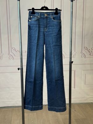 jeans hanging on a clothes rack in front of a white wall