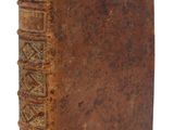 un vieux livre à la couverture brune posé sur une surface blanche