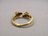 un gros plan d'une bague en or d'où sort la tête d'un serpent