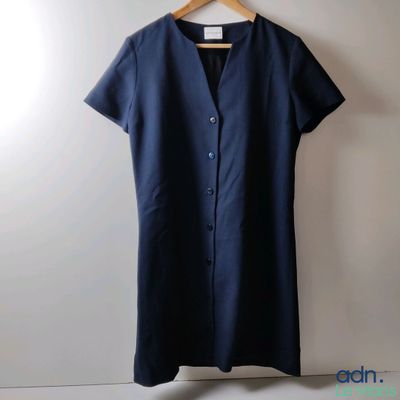 une robe bleue suspendue à un cintre devant un mur blanc