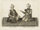 two men sitting on a rug talking to each other