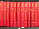Six livres rouges sont alignés sur une surface noire, avec une banane devant eux