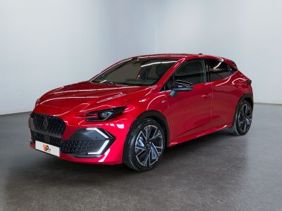 Une voiture rouge est garée dans une pièce blanche au sol noir