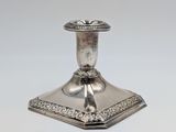 an antique silver candle holder with ornate design on a white background