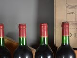 three bottles of red wine are lined up on a shelf