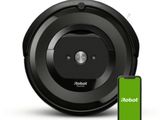 un aspirateur robot noir avec une batterie verte à côté