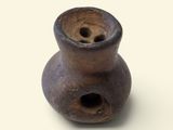 un vase marron percé d'un trou, posé sur une surface blanche