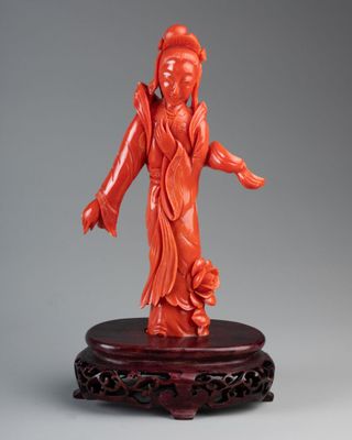 a red carved figurine of a woman on a stand