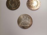 three silver coins are on display in a glass case