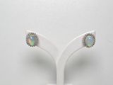 une paire de boucles d'oreilles en oplite et diamants, présentée sur un présentoir blanc