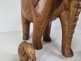 a wooden elephant and a baby elephant standing next to each other