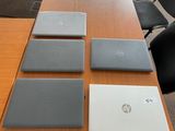 quatre ordinateurs portables posés sur une table dans une salle de réunion