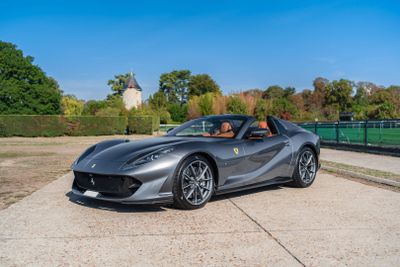 a grey ferrari sports car parked in front of a park