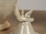 a white vase and a bird figurine on a table