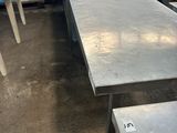 Plusieurs tables en acier inoxydable sont alignées dans une pièce
