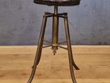 une photo d'un tabouret avec une assise en cuir posé sur un plancher en bois