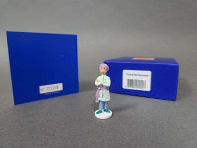 une petite figurine représentant une femme debout à côté d'une boîte bleue