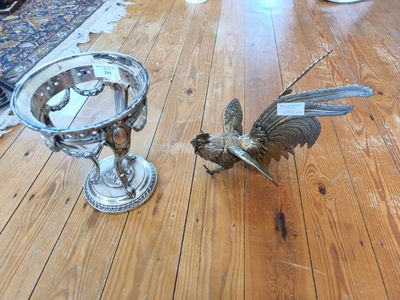 un oiseau posé par terre à côté d'un bol en argent