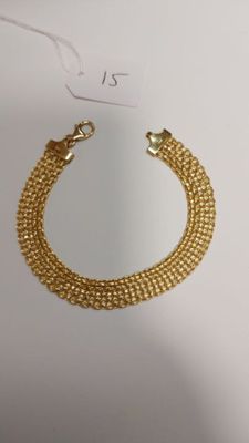 a close up of a gold chain bracelet on a white surface