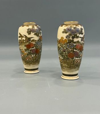 pair of asian vases with flowers and trees on them on a gray surface