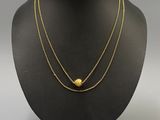 a gold necklace with a ball and chain on a mannequin