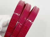 three pieces of red leather are held in a person ' s hand