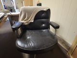 a black leather chair in a room with a man in the background