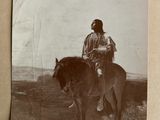 an old photo of a man riding a horse in a field