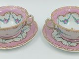 deux tasses à thé roses et dorées avec leurs soucoupes, posées sur une surface blanche