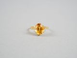 un gros plan d'une bague sertie d'un saphir jaune sur une surface blanche