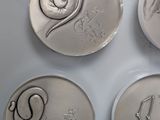 three silver coins with the names of different zodiacs on them