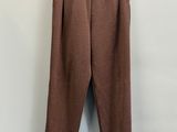 a brown pants hanging on a hanger against a white wall
