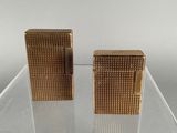 pair of gold tone cigarette lighters on clear acrylic stand