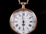 a gold pocket watch with roman numerals on the face