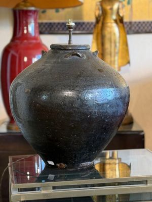 a black vase sitting on top of a glass table next to a lamp