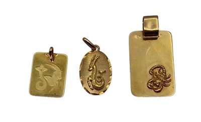 un gros plan sur trois pendentifs en or sur fond blanc