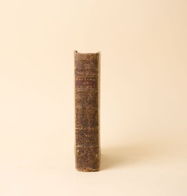 un vieux livre posé sur une table à côté d'un mur blanc