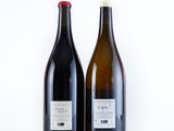 two bottles of wine sitting next to each other on a white surface
