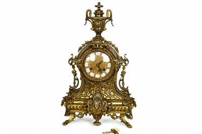 une horloge en or posée sur une table, à côté d'une clé