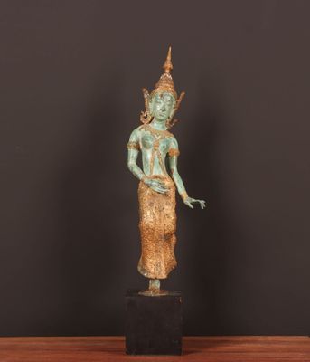 une statue en bronze représentant une personne debout sur une table en bois