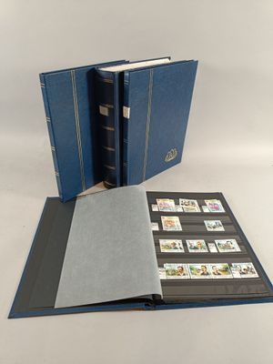 un livre bleu ouvert, orné de timbres, posé sur une table
