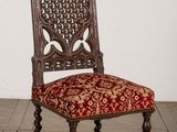 une vieille chaise en bois avec une assise rembourrée rouge, posée sur un parquet
