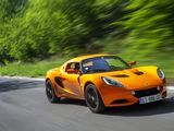 an orange sports car driving down a road with trees in the background