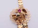 a gold necklace with a pink stone in the middle of it