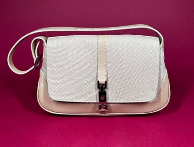 a white purse with a metal handle on a pink background