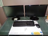 deux écrans d'ordinateur et un clavier posés sur un bureau en verre