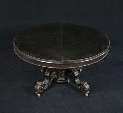 La table est en bois et son plateau est en cuir noir.