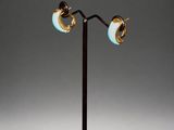 a pair of blue and gold earrings on a black stand