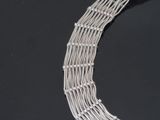 a close up of a silver necklace on a black surface