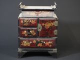 une petite commode en bois décorée de fleurs et de feuilles